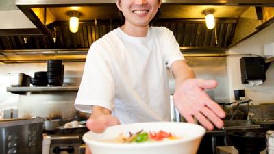 Smiling man serves ramen